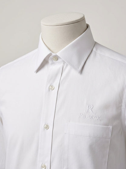 A white long-sleeve button-down dress shirt with a pointed collar and a chest pocket, displayed on a mannequin torso. The brand name 'Ribotex' is subtly embroidered in tonal white on the left chest pocket.